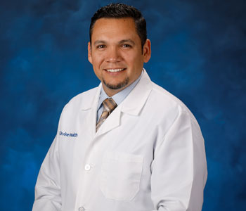 uci health family medicine physician dr jose mayorga with a studio blue background wearing a white coat; he has been named as one of becker's hispanic latino leaders to know