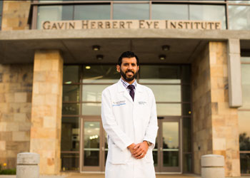 uci health ophthalmologist dr sumit garg wearing a white coat standing in front of the gavin herbert eye institute in irvine