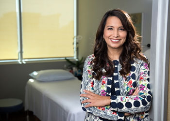 dr. shaista malik, uci health physician and founding executive director of the susan samueli integrative health institute, standing in a doorway in front of a treatment room