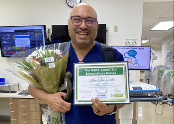 uci health fountain valley nurse alfred jamarillo holds his daisy award certificate bouquet of flowers and healer's touch sculpture