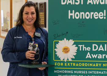 uci medical center in orange nurse janette sanches holds her healer's touch sculpture in front of a sign congratulating her on the daisy award