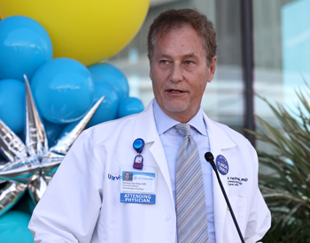 uci health hematologist oncologist dr richard van etten wearing a white coat standing in front of blue and yellow balloons speaks at the opening of the chao family comprehensive cancer center at uci health irvine