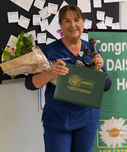 uci health nurse jacqui ogilvie standing with her DAISY award and certificate