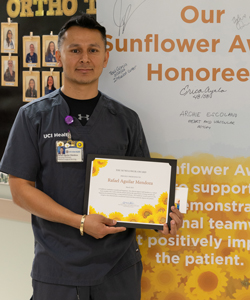 uci health orthopedic assistant rafael aguilar standing with his sunflower award and certificate
