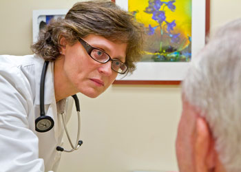 uci health geriatrician dr lisa gibbs examines an older adult patient while wearing a white coat and stethoscope