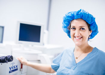 uci health ophthalmologist dr marjan farid at the gavin herbert eye institute wearing a head cover and blue scrubs in a bright room with medical equipment