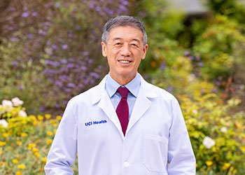 Dr. Gary Deng, director of Integrative Oncology at the UCI Health Chao Family Comprehensive Cancer Center, stands in front of a natural garden area outside the Susan Samueli Integrative Health Institute in Irvine.