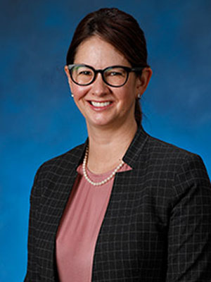 uci health neuropsychologist hayley b kristinsson wearing a dark jacket in front of a blue studio background