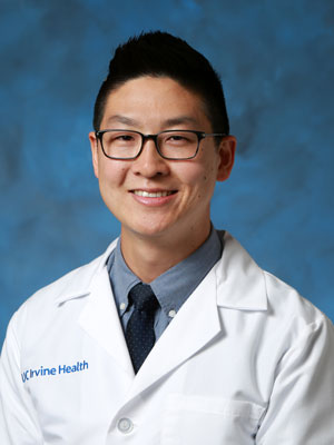 uci health sports medicine specialist dr brian kim in front of a blue studio background and wearing a white coat