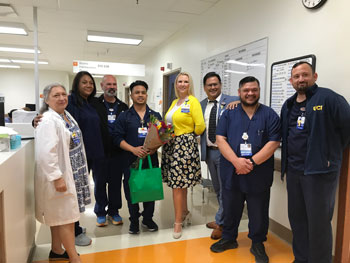 uci health fountain valley nurse adrian belonia celebrates his daisy award and holds flowers with his co-workers