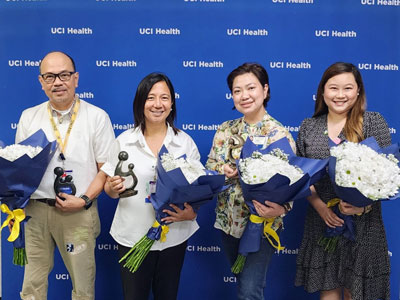 uci health lakewood nurses Ron Santiago, Lizzelle Leonida, Evangeline Ong and Melody Santos stand in front of a uci health step and repeat with daisy awards
