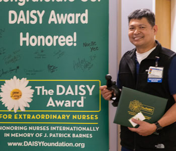 uci health lakewood nurse pat evangelista holds her daisy award and certificate 
