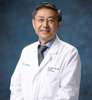 Dr. Qin Yang, endocrinologist and the director of the UCI Health Diabetes Center, sitting in front of a blue background wearing a white coat