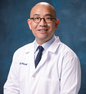 uci health radiation oncologist dr david hong wearing a white coat in front of a blue studio background