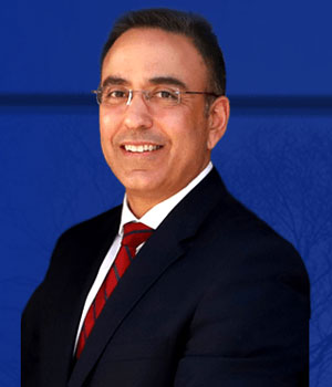 uci health orthopedic spine surgeon dr nitin bhatia wearing a dark suit in front of a blue background