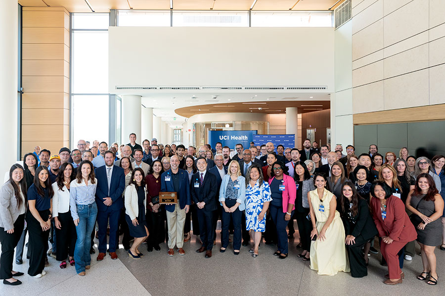 An excited group of UCI Health co-workers and leaders gather in the lobby of UCI Health — Irvine to celebrate receiving the keys to the new acute care hospital so that final touches can be added before opening day.