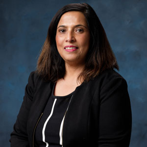 uci health chief medical information officer depti pandita wearing a dark suit in fron of a blue studio background