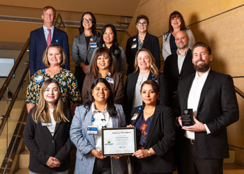 the uci health risk and regulatory affairs team stands on stairs and holds their spotlight innovation award for their fire safety risk assessment project, which has prevented fires since implementation