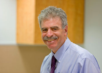 uci health pediatrician and uc irvine school of medicine researcher dr dan cooper in an office wearing a shirt and tie with cabinets behind him