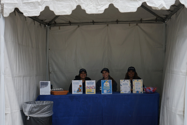 volunteer services table at uci health irvine acute care hospital community event on cloudy rainy day