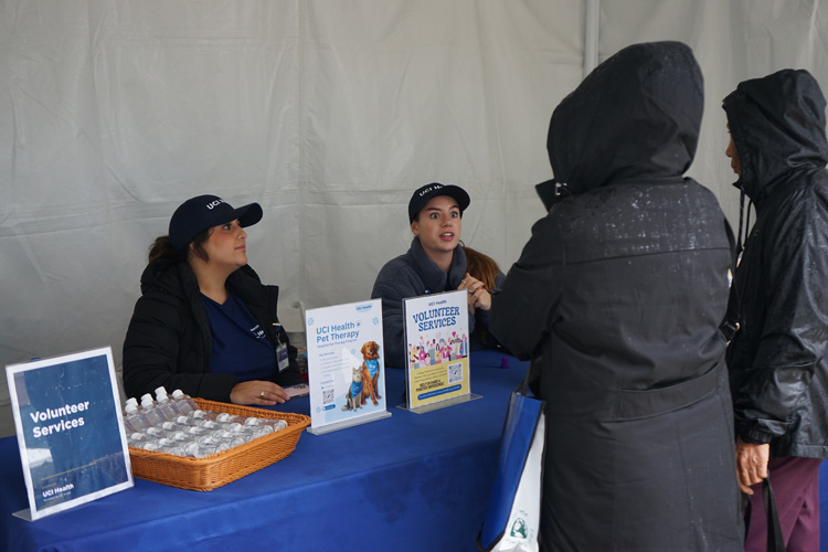 volunteer services table at uci health irvine acute care hospital community event on cloudy rainy day