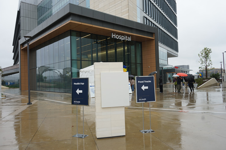 signs point to food trucks and health fair at uci health irvine community event on rainy cloudy day