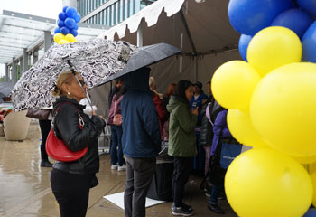 people check in at the health fair booth amid blue and yellow balloons at the uci health irvine hospital community event