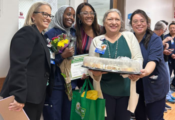 uci health fountain valley daisy winner raadhiya zekeria celebrates with her team while holding her healer's touch sculpture and a certificate
