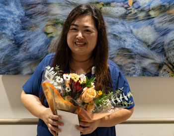 uci health inaugural nurse leadership award winner khristine felix holds flowers and is wearing scrubs
