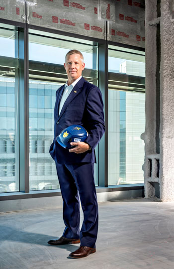 uci health — irvine senior project manager jess langerud stands inside a construction area with a hard hat and wearing a suit