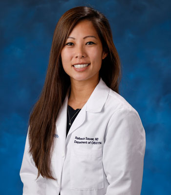 uci health obstetrician and gynecologist dr rebecca sauer wearing a white coat seated in front of a blue studio background