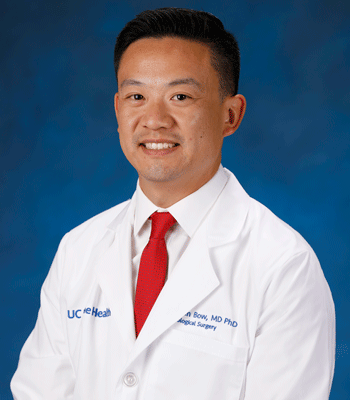 uci health neurosurgeon dr hansen bow in front of a blue studio background wearing a white coat