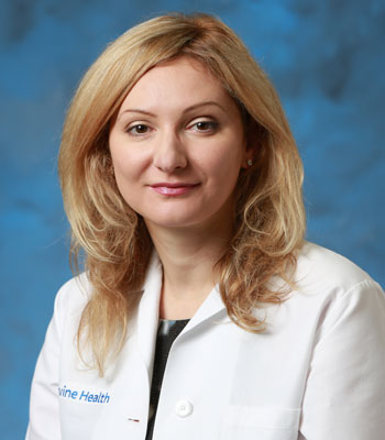 uci health dermatologist dr. natasha mesinkovska wearing a white coat in front of a blue studio background