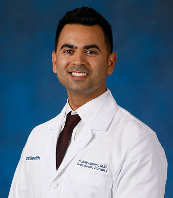 uci health orthopedic surgeon dr. sohaib hashmi in a white coat in front of a blue studio background