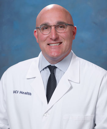 uci health kidney transplant surgeon dr robert redfield iii in a white coat in front of a blue studio background