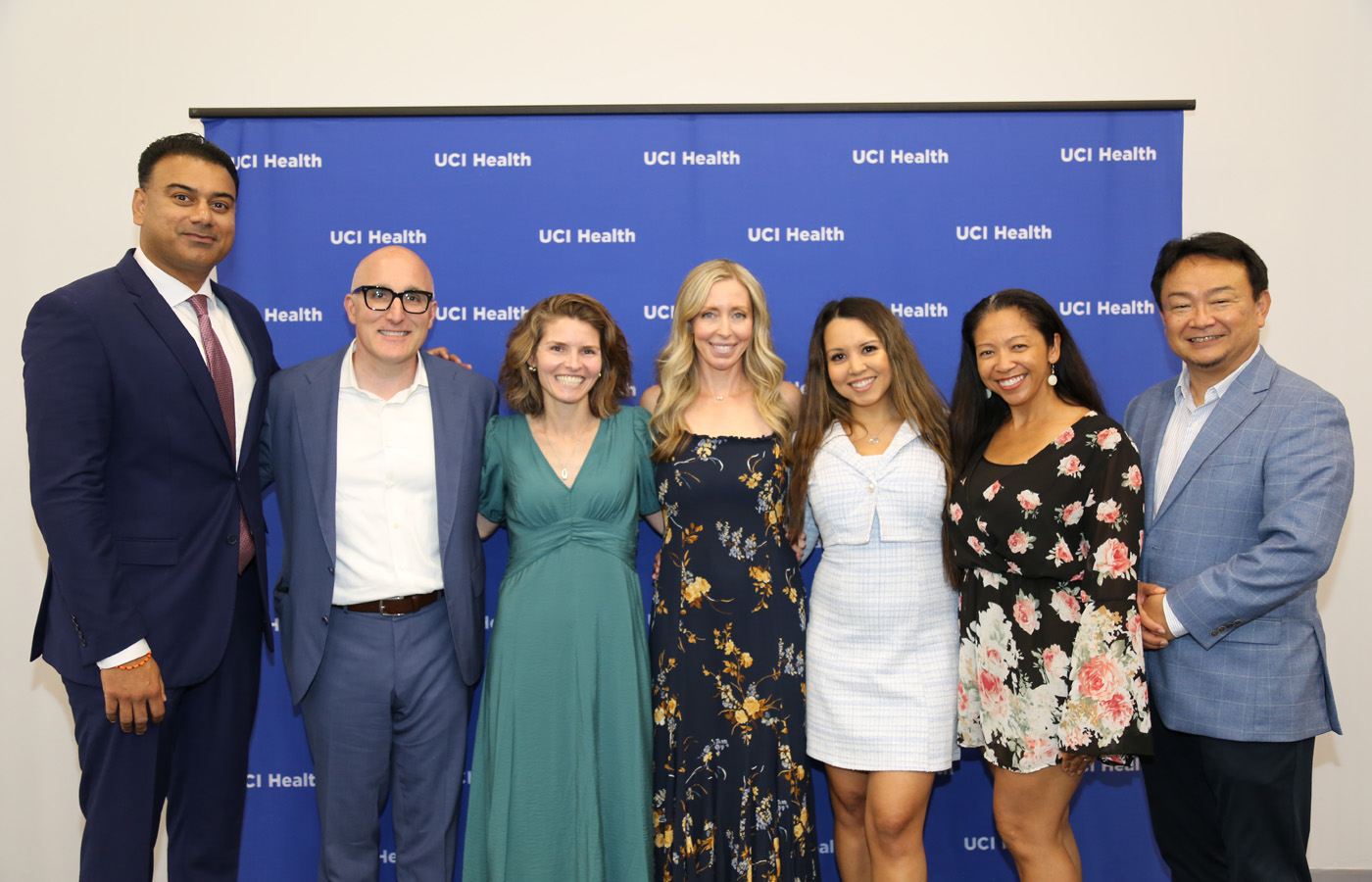 uci health kidney transplant recipients, donors and program co-workers celebrate at a special honorary event in April in front of a blue uci health step and repeat
