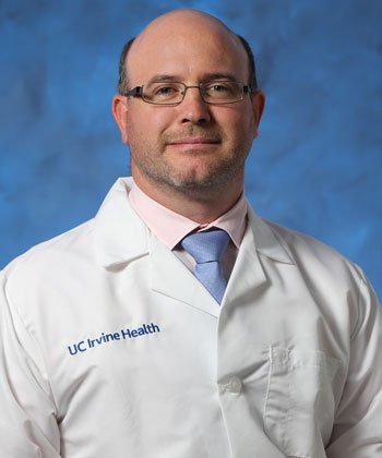 uci health neurologist dr nicolas phielipp wearing a white coat in front of a blue studio background