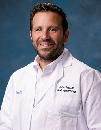 uci health gastroenterologist dr robeert fearn wearing a white coat and sitting in front of a blue background