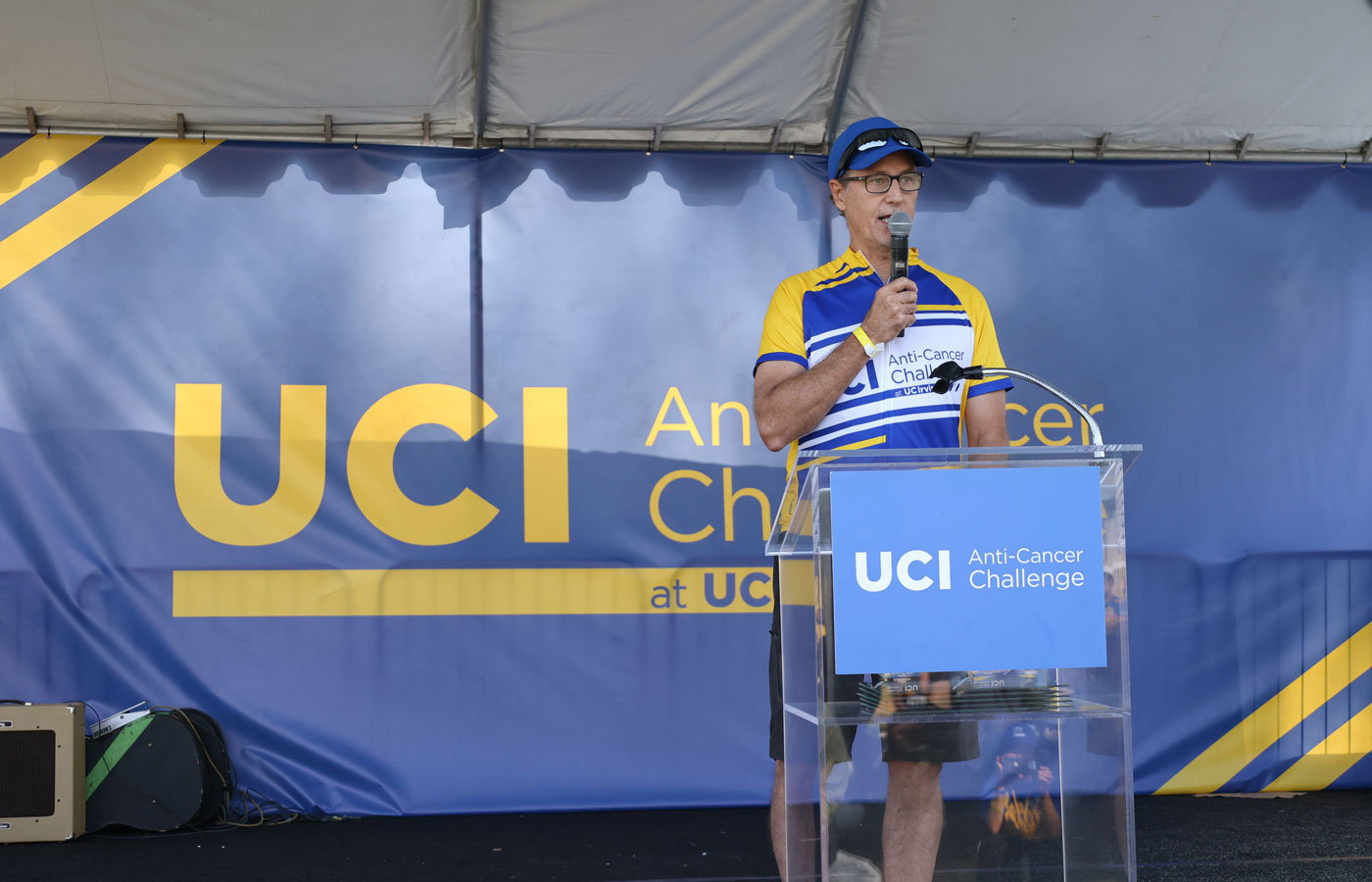 uci health chao family comprehensive cancer center medical director dr richard van etten speaks on stage wearing a uci cycling jersey