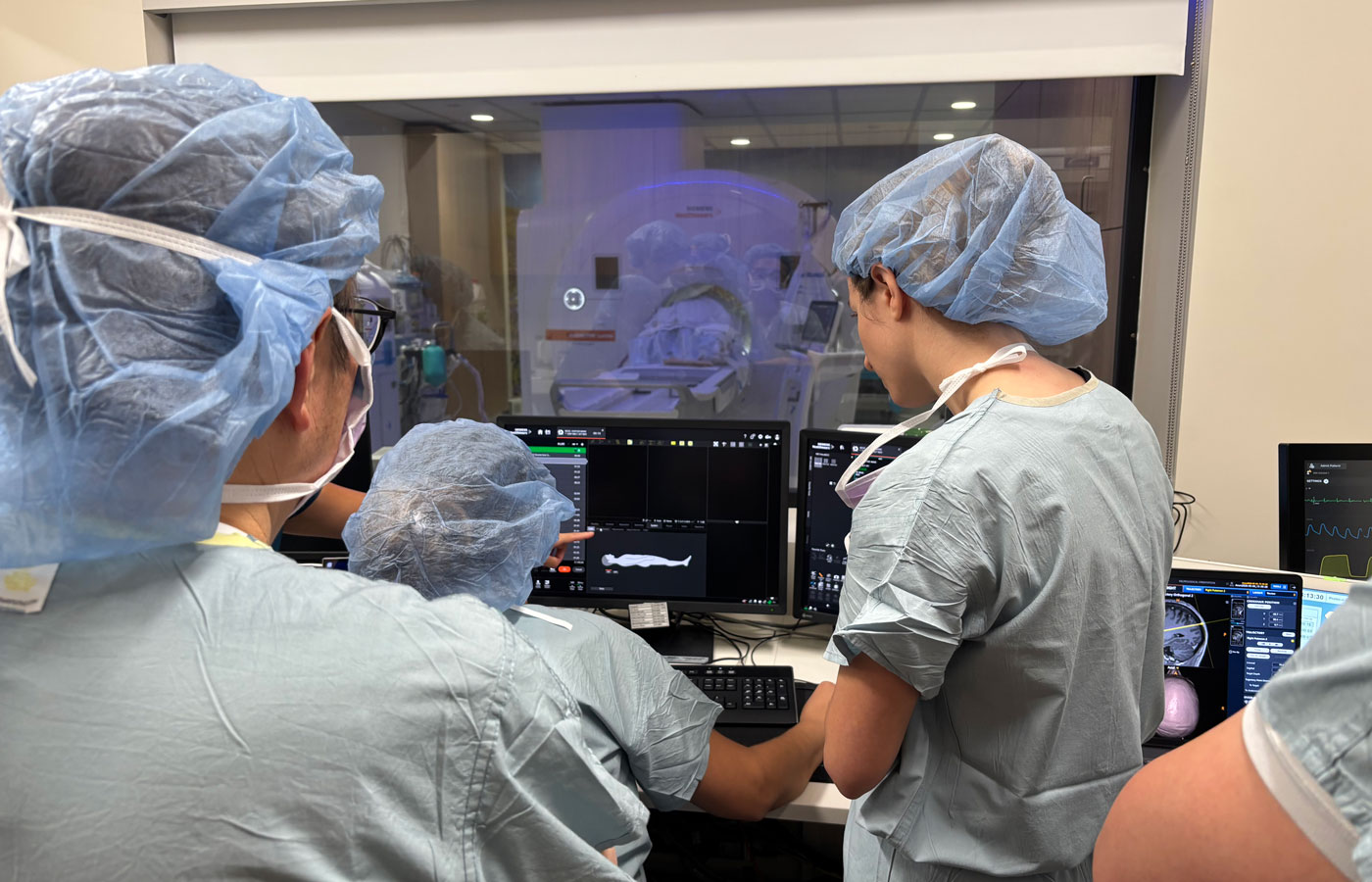 the huntington's disease clinical trial team in scrubs treats their first patient, who is in an MRI on the other side of the window