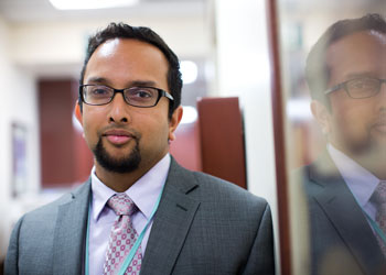 uci health gastroenterologist dr jason samarasena wearing a suit in a hospital hallway reflected in a window next to him