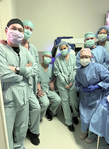the uci health robotic assisted surgery team gathers for a photo while wearing scrubs to celebrate their milestone in pancreatic cancer treatment