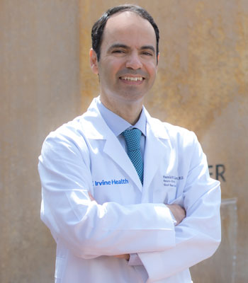 uci health otolaryngologist wearing a white coat during an outdoor photo in front of the healing garden fountain at uci health - orange