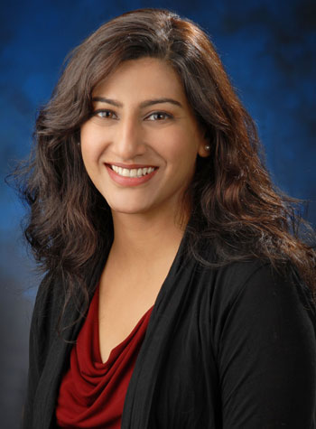 uci health infectious disease expert dr shruti gohil wearing a suit in front of a blue studio background