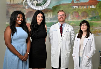 Onwodi Ifejeokwu, lead CAR T-cell study author Atena Zahedi, UC Irvine assistant professor of clinical pharmacy practice, Shawn Griffin and Dr. Erin Dean stand in front of a painting under a boom light