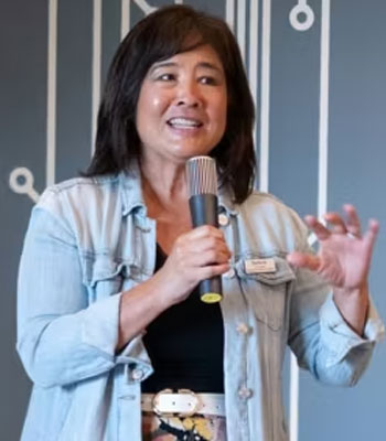 uci health patient relations manager stefanie yoshii speaks into a microphone during a trauma intervention program of orange county (tip) event