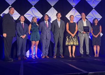 uci health clinicians pose on stage with their first responder awards from the orange county business council, standing from left to right:   Jeffrey Ball, president and chief executive officer, Orange County Business Council  Nathan Shinagawa  Carly Passaglia, RN, BSN, MICN, UCI Health – Orange emergency department  Dr. Eric Wang  Dr. Tyler Johnston  Dr. Carrie Chandwani  Dr. Michael Lekawa  Hetty Chang, NBC 4 Orange County reporter