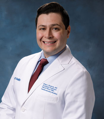 uci health cardiologist dr brian becerra wearing a white coat in front of a blue studio background