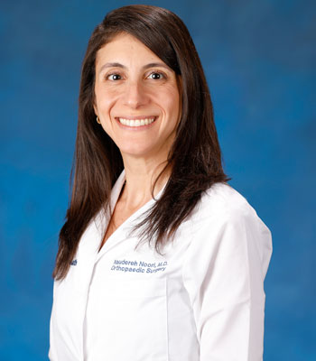 uci health orthopaedic foot and ankle surgeon dr. naudereh noori wearing a white coat in front of a blue studio background