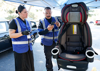 Two UCI Health FQHC workers inspect a car seat.
